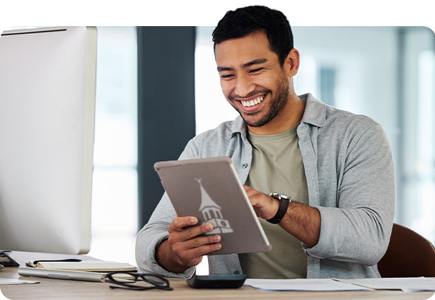Man sitting at desk navigating on a table device.