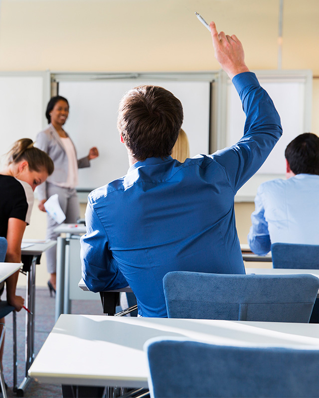 student raising hand in a classroom setting