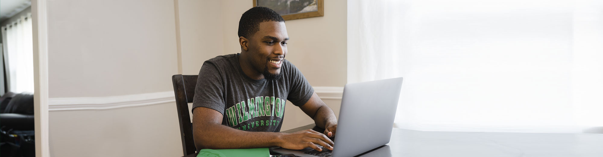 Male student sitting at table on laptop