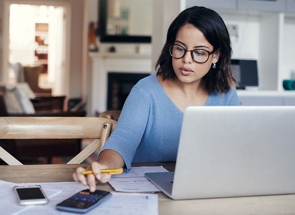 Woman working at computer with documents and calculator